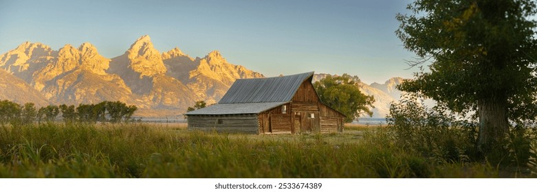 Scenic view of a rustic barn with the Grand Teton mountains in the background during sunset in Wyoming - Powered by Shutterstock