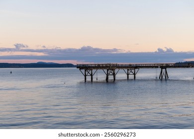 Scenic view of a rustic wooden pier stretching over calm waters during sunset, with serene reflections and a colorful horizon. A peaceful setting on Vancouver Island, perfect for relaxation - Powered by Shutterstock