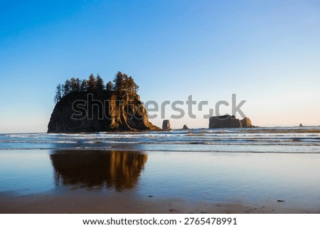Scenic view of Second Beach at sunset in Olympic National Park, Washington State. Dramatic sea stacks, golden sky, and peaceful waves along the rugged Pacific Northwest coast.