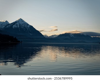 Scenic view of snow-capped mountains reflecting on a tranquil lake at sunset, capturing serene natural beauty. - Powered by Shutterstock