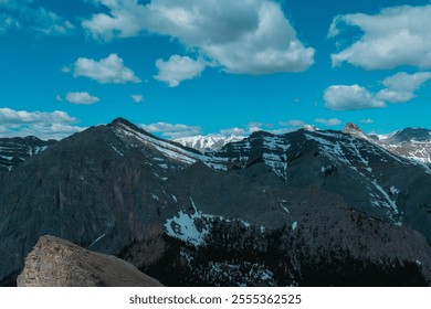 A scenic view of snow-capped mountains under a blue sky with scattered clouds. - Powered by Shutterstock