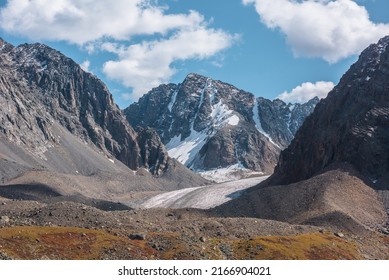 Scenic view to sunlit rocks and large snow mountain top with glacier in autumn sunny day. Vivid autumn colors in high mountains. Motley landscape with sharp rocks and snow mountain peak in bright sun. - Powered by Shutterstock