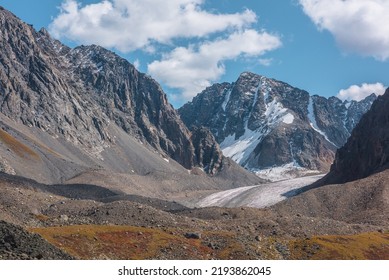 Scenic View To Sunlit Rocks And Large Snow Mountain Top With Glacier In Autumn Sunny Day. Vivid Autumn Colors In High Mountains. Motley Landscape With Sharp Rocks And Snow Mountain Peak In Bright Sun.