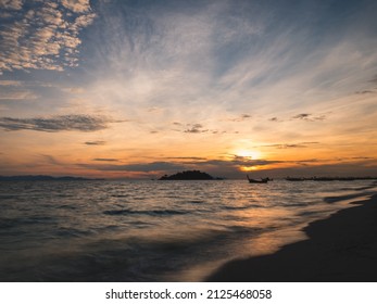 Scenic View Of Sunrise And Motion Blurred Wave On Tropical Island Beach With Local Longtail Boat And Small Island Silhouette. Sunrise Beach, Koh Lipe Island. Satun, Thailand. Long Exposure Seascape.