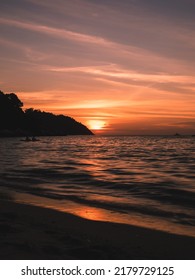 Scenic view of Sunset Beach, Koh Lipe Island. Dramatic sunset orange sky with sunlight reflection on sea water waves. Satun, Thailand. Long exposure, blurred wave motion.