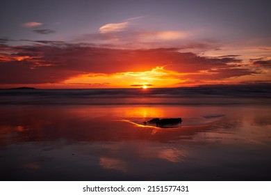 A scenic view of sunset over a body of water with the colorful sky reflected on it