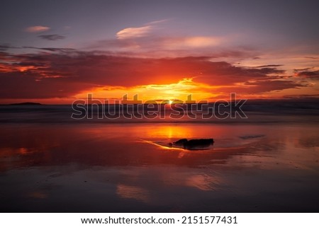 A scenic view of sunset over a body of water with the colorful sky reflected on it