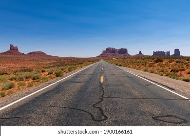 Scenic View Of Ta Road Leading To The Monument Valley With Sandstone Buttes On The Background; Concept For Travel In The USA And Road Trip.