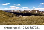 Scenic view from Trail Ridge Road in Rocky Mountain National Park, Colorado. Snow-capped peaks, alpine meadows, and dramatic summer skies stretch across the mountain landscape.