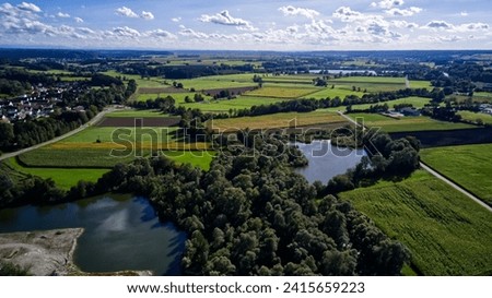 A scenic view of a tranquil countryside landscape featuring lush green farmlands and a tranquil lake.
