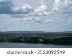 Scenic view of a tranquil lake surrounded by lush forests and cloudy sky in Hollola, Finland