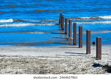 Scenic view of wooden posts on a sandy beach with the blue ocean in the background. Perfect for backgrounds, travel, and nature-themed projects - Powered by Shutterstock