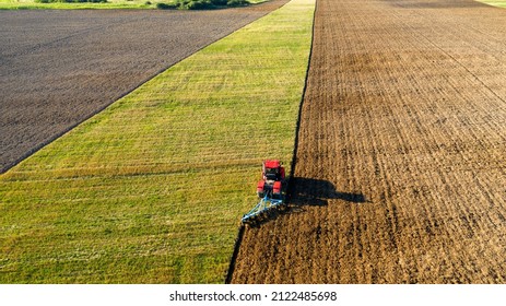 Scenic View Of Working Tractor In The Field Agricultural Field On A Summer Farm In The Evening. Aerial Photography, Top View Drone Shot. Agricultural Area Of Moscow Region. Agrarian Land In Summertime