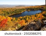 Scenic vista of brilliant fall colors in the woods surrounding Lake Solitude on Mt. Sunapee in Newbury, New Hampshire in autumn.