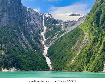 Scenic waterfall, partly frozen, with meltwater from icy mountaintop along Tracy Arm fjord on a sunny morning early in summer in southeast Alaska - Powered by Shutterstock