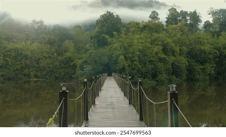 Scenic wooden bridge stretching across serene lake, surrounded by lush green forest and misty mountains in background, evoking tranquility and natural beauty. Nature and Serenity. - Powered by Shutterstock