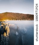 Scennic foggy view above the frozen trees. Mysterious Winter road in the forest. Majestic aerial sunrise nature background 