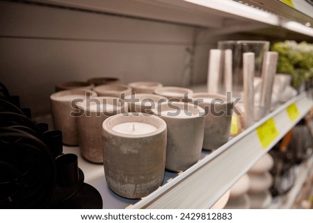 Scented aroma candles in plaster candlestick standing on rack at store