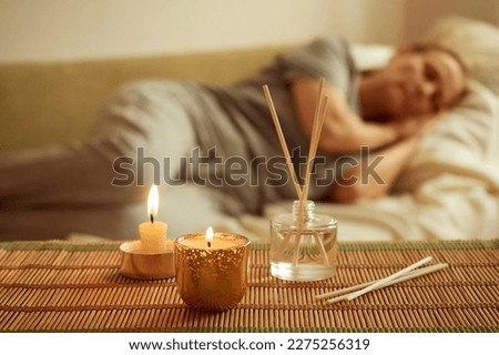 Scented candle, diffuser, sleeping woman in the background. The concept of relaxation, mental health