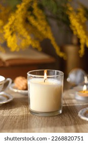 Scented candles, on the table. Selective focus.chocolate, cookies, cup of tea, books, e-reader, glasses and flowers on the table. Hygge at home. Selective focus.