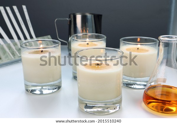 scented candles are on white table with\
fragrance, essential oil bottles and blotters testing paper during\
the blending scent for making perfume and candle by the perfumer in\
the laboratory