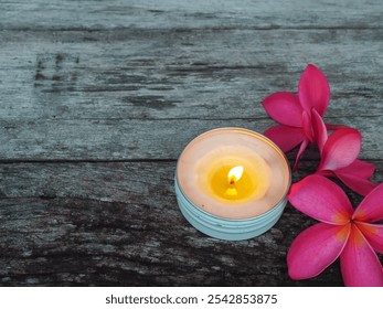 Scented candles with pink frangipani flowers on old wooden table about relaxation and spa    - Powered by Shutterstock