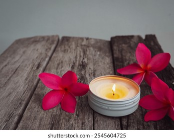 Scented candles with pink frangipani flowers on old wooden table about relaxation and spa     - Powered by Shutterstock