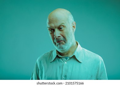 Sceptical senior man pulling a disbelieving face as he glances sideways with a dubious expression on blue