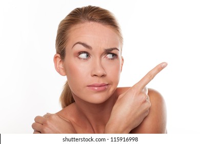 Sceptical woman with one eyebrow raised pointing with her finger to the right of the frame isolated on white