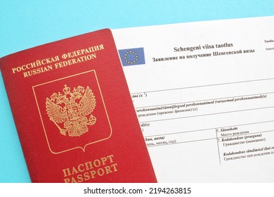 Schengen visa application form in Russian and Estonian language and passport on blue background. Prohibition and suspension of visas for Russian tourists to travel to Europe Union and Baltic States - Shutterstock ID 2194263815