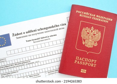 Schengen visa application form in Russian and Czech language and passport on blue background. Prohibition and suspension of visas for Russian tourists to travel to European Union and the Baltic States - Shutterstock ID 2194265383