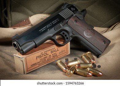 Schererville, Indiana/United States Aug 8, 2018. Colt model 1911 lightweight Commander 45 ACP with vintage cartidges and 20 round box against a tan canvas background