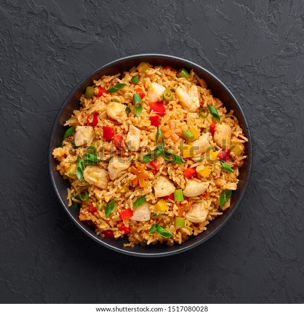 Schezwan\
Chicken Fried Rice in black bowl at dark slate background. Szechuan\
Rice is indo-chinese cuisine dish with bell peppers, green beans,\
carrot, chicken breasts. Copy space. Top\
view