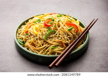 Schezwan Noodles or Szechwan vegetable Hakka Noodles or chow mein is a popular Indo-Chinese recipes, served in a bowl or plate with wooden chopsticks