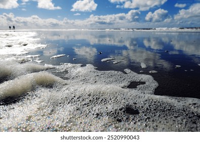 Schiermonnikoog, Unesco World Heritage, beautiful colorful mirror reflections of the white clouds and blue sky above the water of the North Sea, 2 hikers on the blurred horizon - Powered by Shutterstock