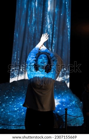 Schizophrenia and enlightenment. Portrait of young woman with closed eyes posing in blue light from illusion of waterfall. Vertical orientation. Concept of psychology, mental health and dreaming.