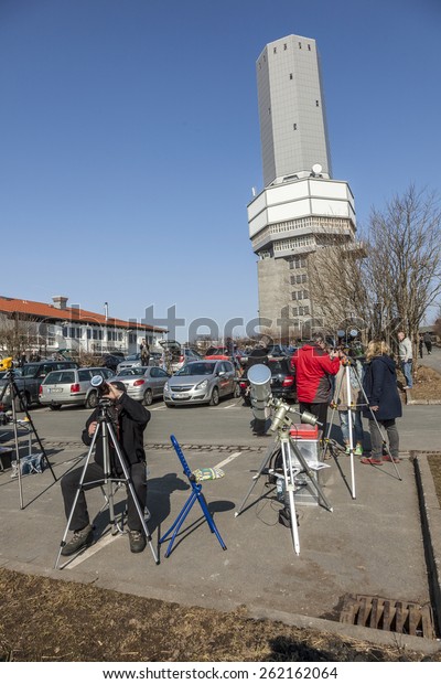 SCHMITTEN, GERMANY - MAR 20, 2014: radio and TV\
station at Mount Grosser Feldberg  in Schmitten, Germany. People\
watch the partial\
eclipse.