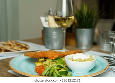 Schnitzel with vegetables and cucumber salad on a table at a restaurant - Shutterstock ID 2301212171
