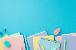 Pink girlish school supplies, notebooks and pens on punchy blue