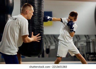 School age boy, beginner boxer practicing punches with personal coach at sports gym, indoors. Concept of studying, challenges, sport, hobbies, competition. Beginning of sports career, future champion - Powered by Shutterstock