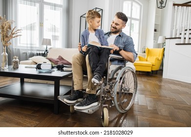 School age child sitting on fathers knees in wheelchair and preparing for school lesson while reading educational book at home. Dad with a disability helping concentrated son finishing homework. - Powered by Shutterstock