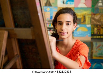 School of art, college of arts. Portrait of happy hispanic girl smiling, learning to paint and looking at camera.