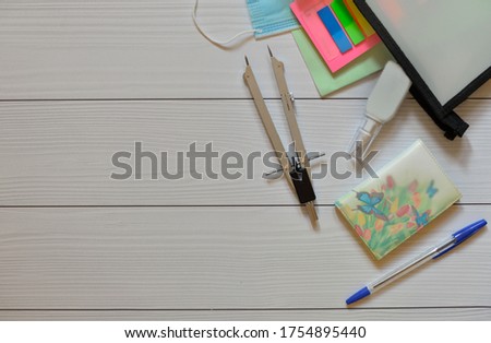 School or back to school concept: divider, small colorful notebook, multicolored sticky notes, blue medical mask (protective mask), pen, folder for notebooks on a wood background