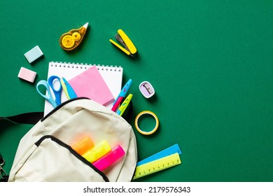 School backpack with colorful stationery on green table. Back to school concept. Flat lay, top view. Back to school concept.