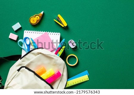 School backpack with colorful stationery on green table. Back to school concept. Flat lay, top view. Back to school concept.