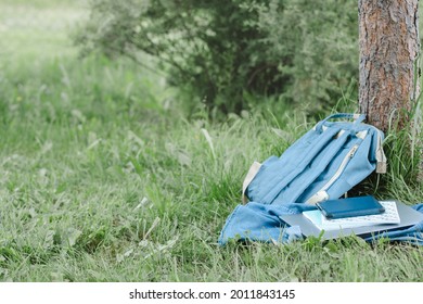 School backpack, laptop, notebook laying in park near tree, copy space