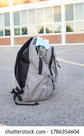 School Backpack With Medical Mask On The Ground At The School Yard. Back To School During Epidemic Concept. 