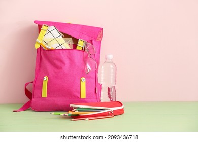 School Backpack With Stationery, Eyeglasses And Bottle Of Water On Table