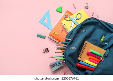 School backpack with stationery supplies on pink background