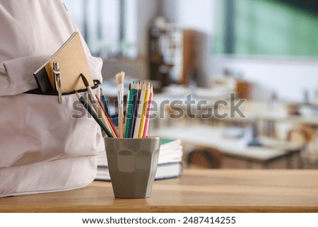 School backpack and school stuff with space for products on wooden desk in  classroom interior. Chalkboard wall background. Back to school. Copy space for school supplies and accessories.